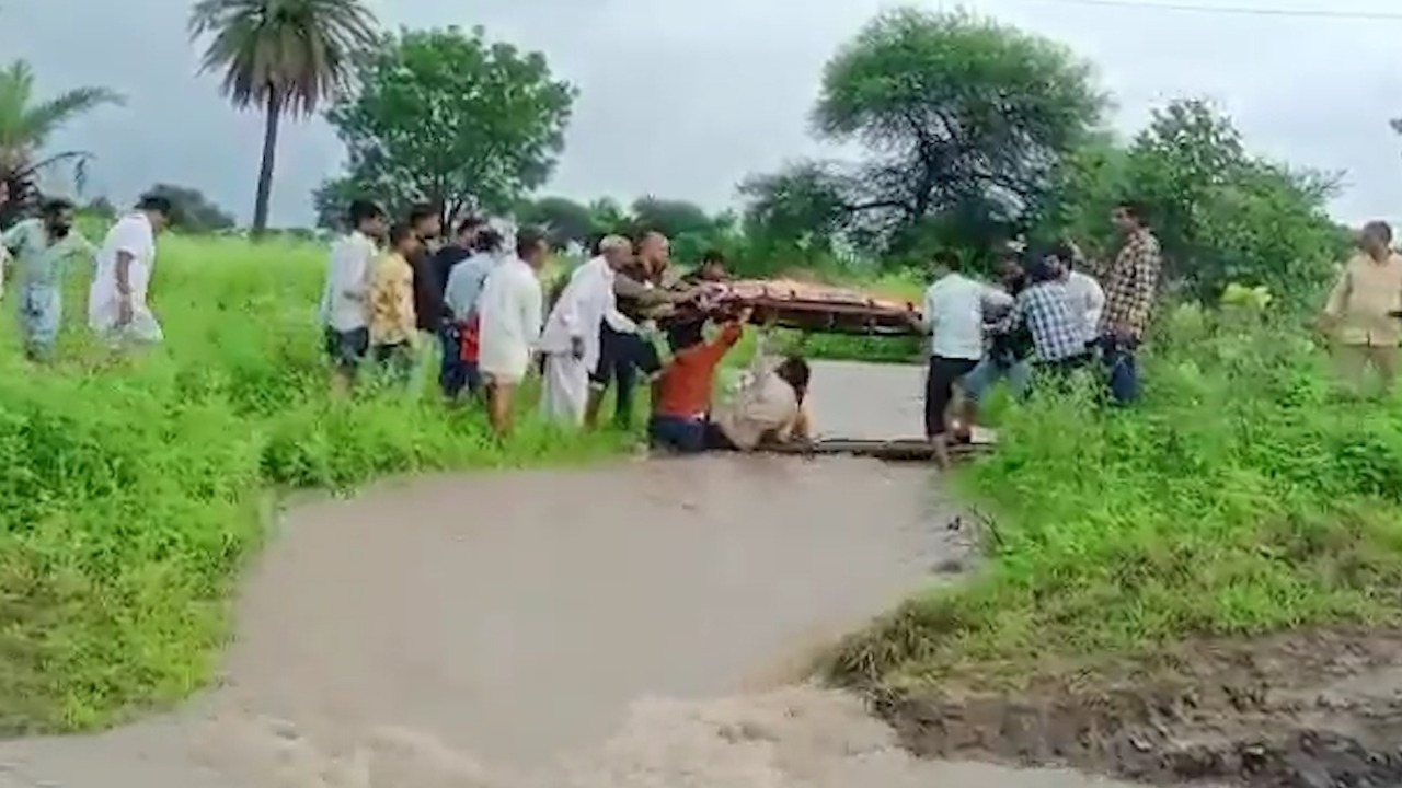 उफनते नाले को पार करने को मजबूर ग्रामीण